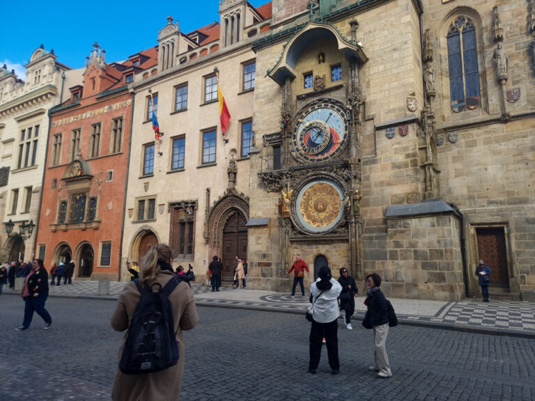 People walking around a city square with a clock tower