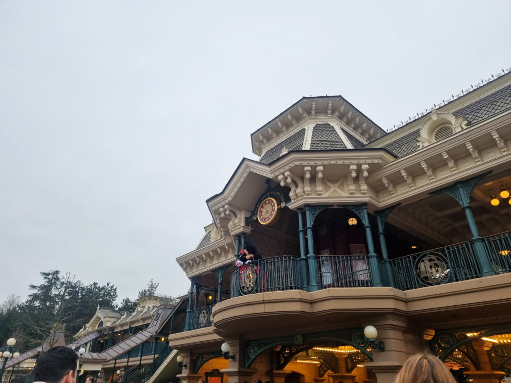 A view of the elegant Main Street U.S.A. architecture, showing a performer in costume waving from the upper balcony of one of the buildings.
