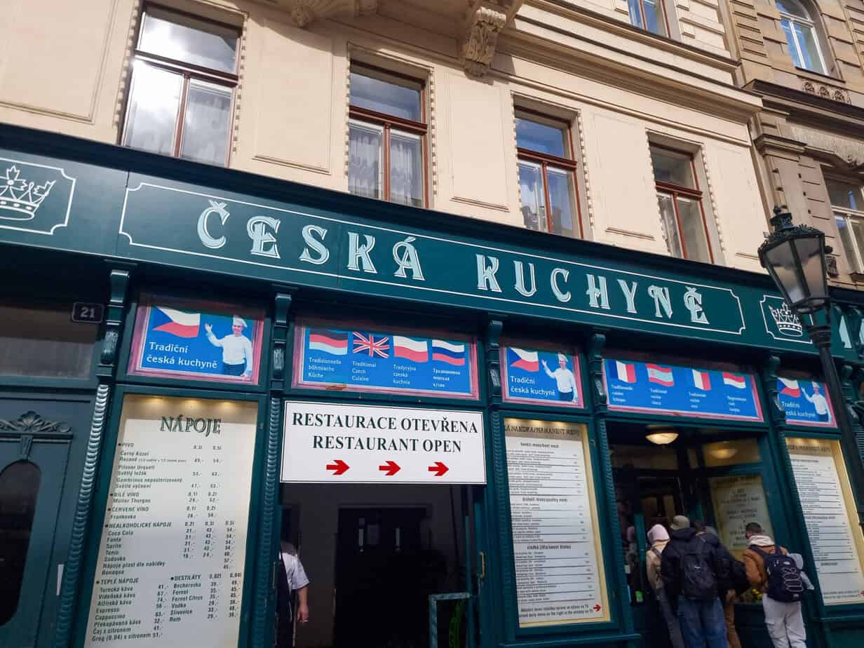 Entrance to Česká Kuchyně, a traditional Czech restaurant with a dark green facade and bilingual signage advertising authentic meals.