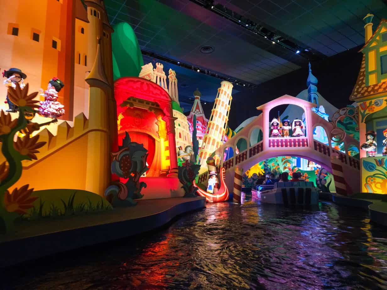 The brightly lit interior of “It’s a Small World” ride at Disneyland Paris, with animatronic dolls representing different cultures set against colorful backdrops, singing the iconic theme song.