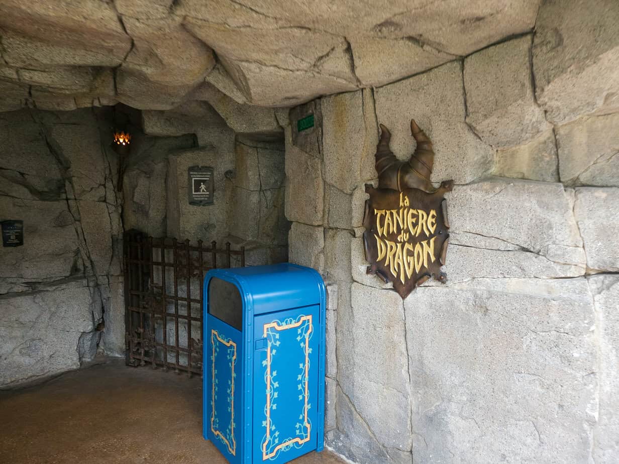 The stony entrance to "La Tanière du Dragon" features a gothic sign with curled horns — an eerie walkthrough and one of the top disneyland paris secrets.