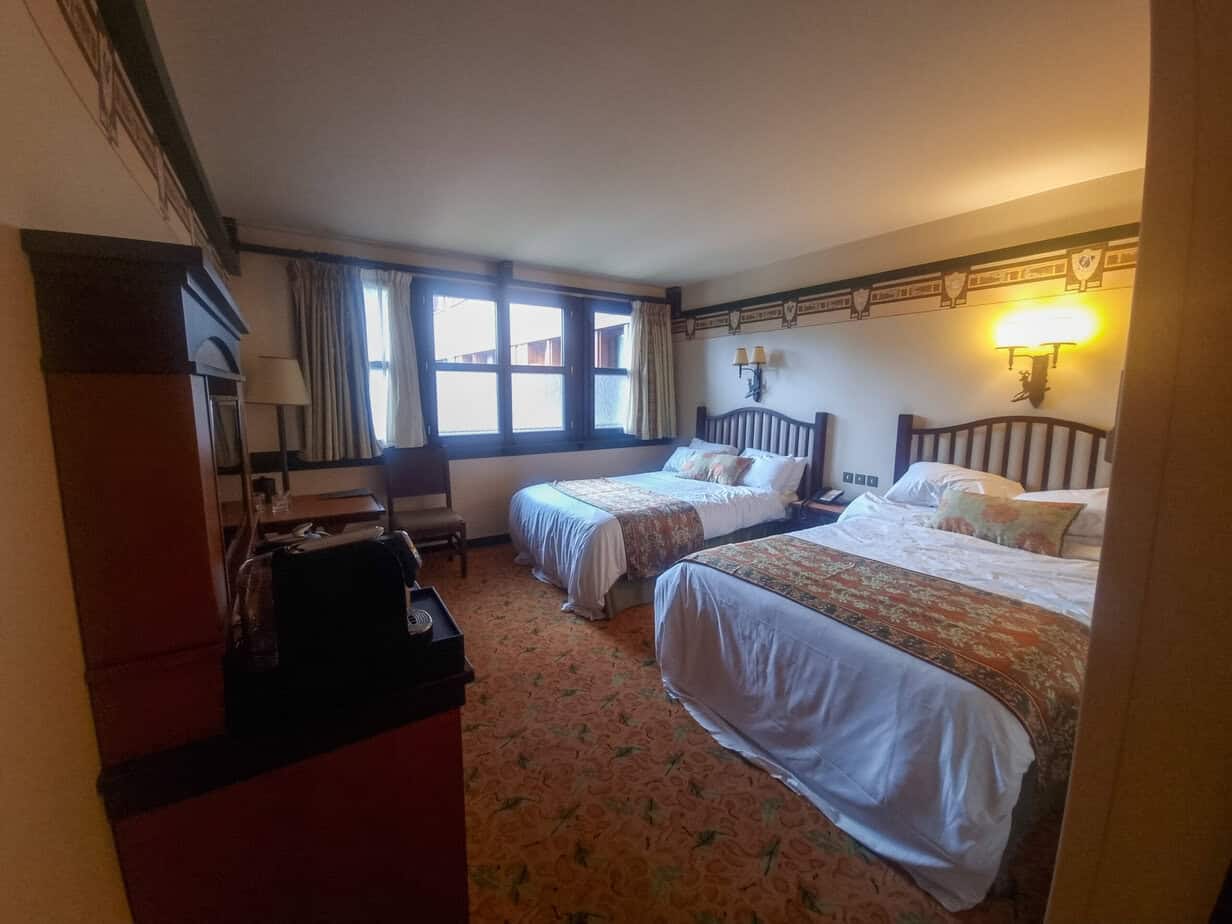 Indoor pool area with rock-inspired decor, natural lighting through large windows, and lounge chairs—one of the relaxing features often found at disneyland paris hotels with pools.
