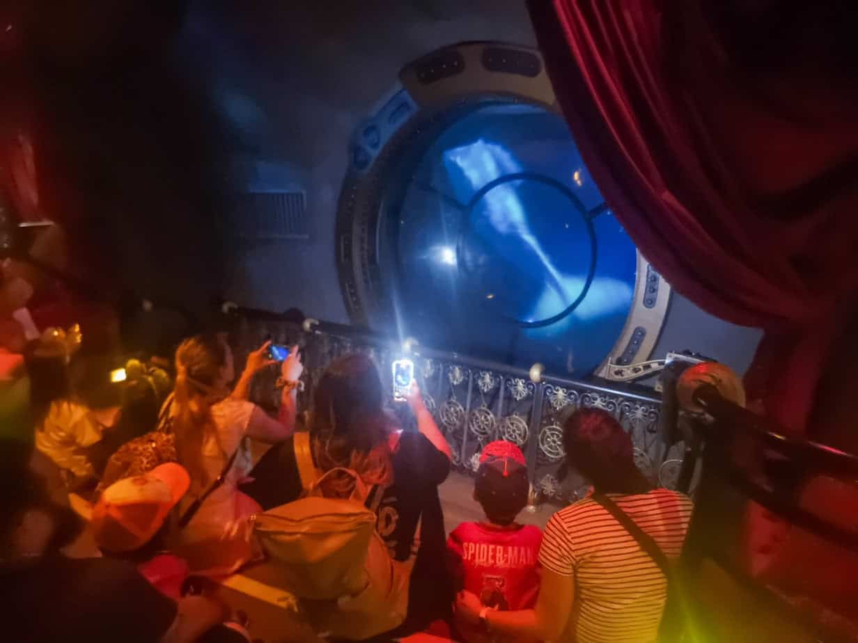 Visitors watch through a porthole-style window inside the Nautilus attraction, where a projected sea creature swims past dramatically — one of the immersive disneyland paris secrets.