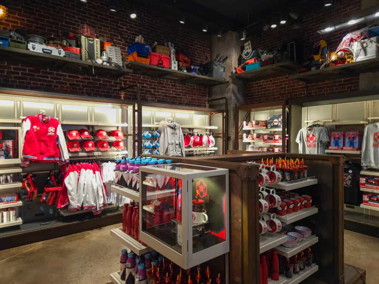 Shelves stocked with Marvel merchandise including caps, jackets, mugs, and toys inside the Mission Equipment store.
