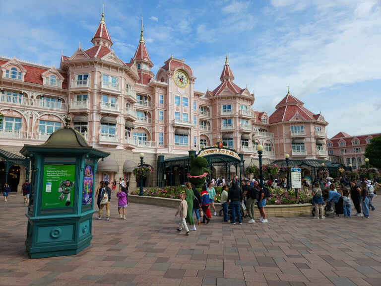 Crowds gather at the grand pink Victorian-style Disneyland Hotel, which serves as the entrance to Disneyland Paris. A perfect spot covered in our Disneyland Paris booking guide.