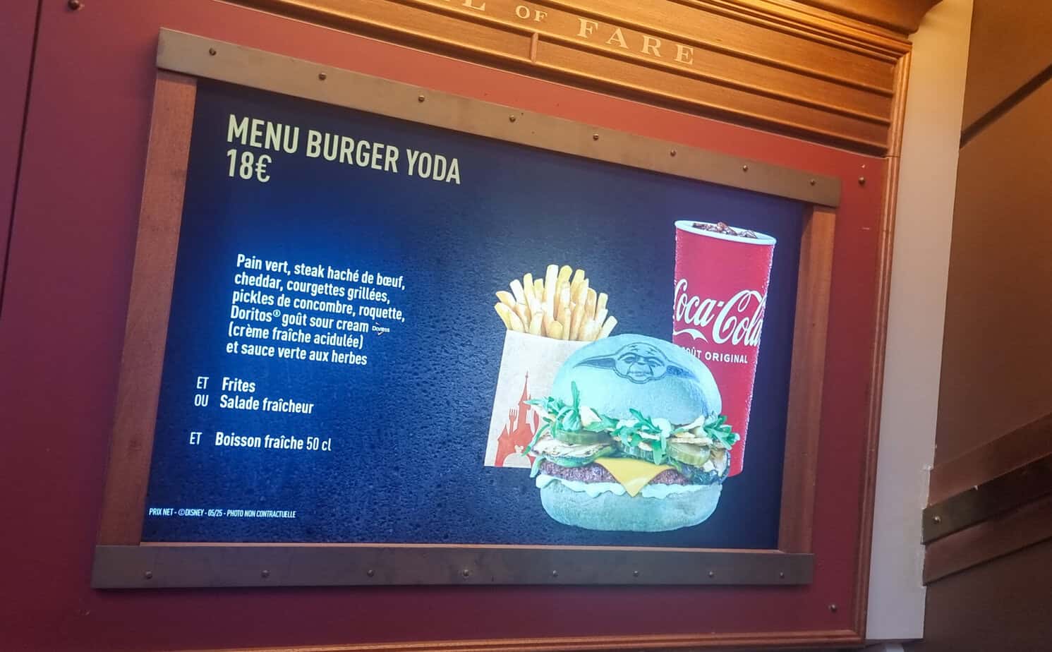 A themed menu displays the “Burger Yoda” meal, featuring a green bun stamped with Yoda’s face, a side of fries or salad, and a drink. French text lists beef, cheddar, grilled zucchini, pickles, and sour cream Doritos as ingredients.