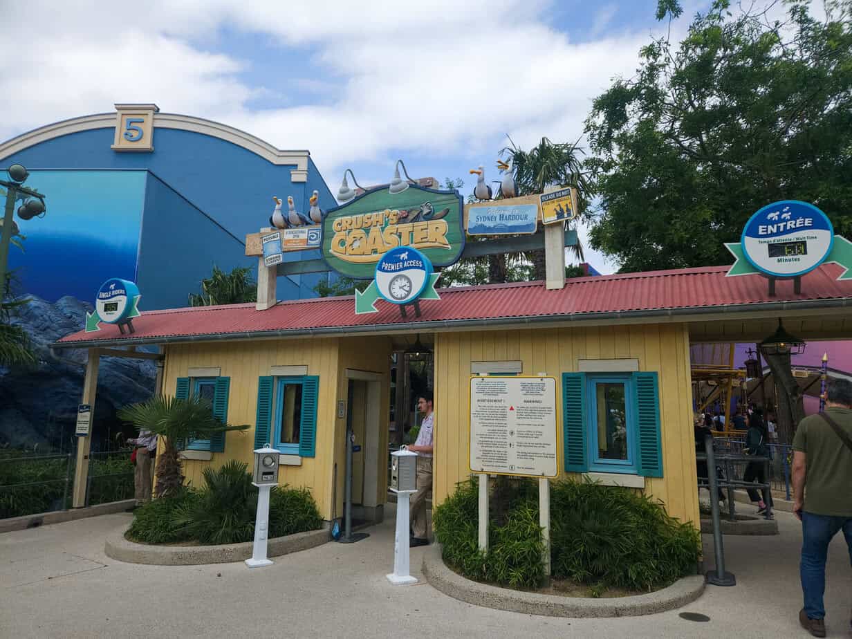Entrance to Crush’s Coaster at Disneyland Paris, styled like a beach shack with colorful signage and a posted wait time, with Disneyland Paris Premier Access signs prominently displayed.