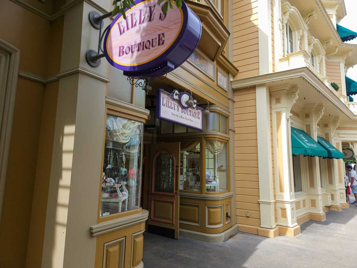 A boutique storefront called “Lilly’s Boutique” with soft yellow walls, purple signage, and a display window filled with elegant merchandise.