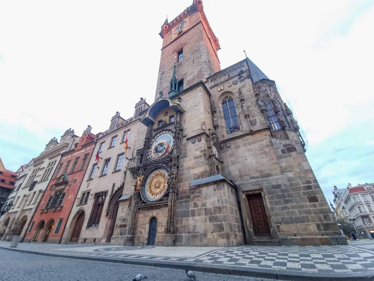 The Prague Astronomical Clock on the side of the Old Town Hall tower features ornate gold details and medieval figures, viewed from a low angle against a bright sky. No 2 day itinerary for Prague is complete without stopping here to see the clock strike the hour.