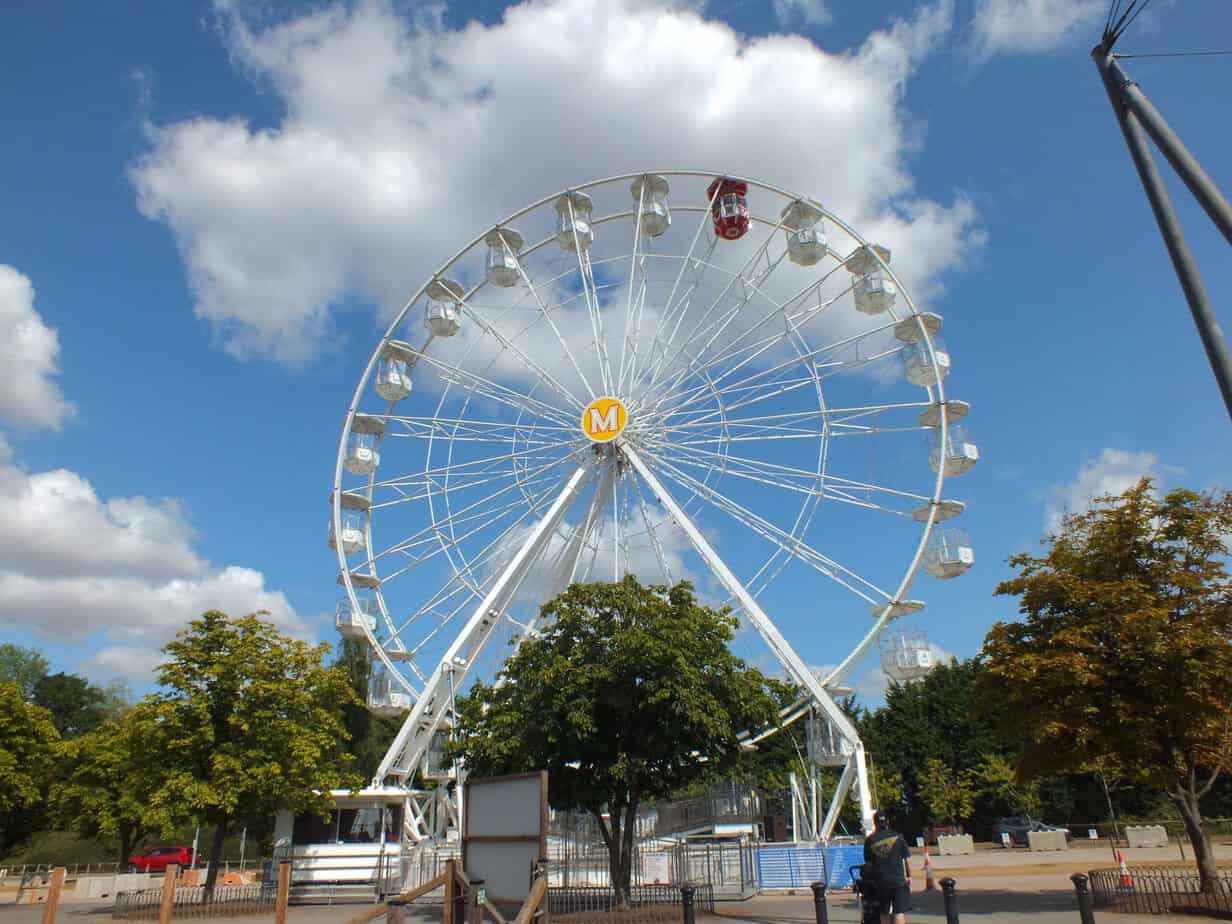 Large white Ferris wheel at Twycross Zoo standing against a bright blue sky filled with white clouds. The extra attraction is one of the features families may consider when deciding whether Twycross Zoo Worth It.