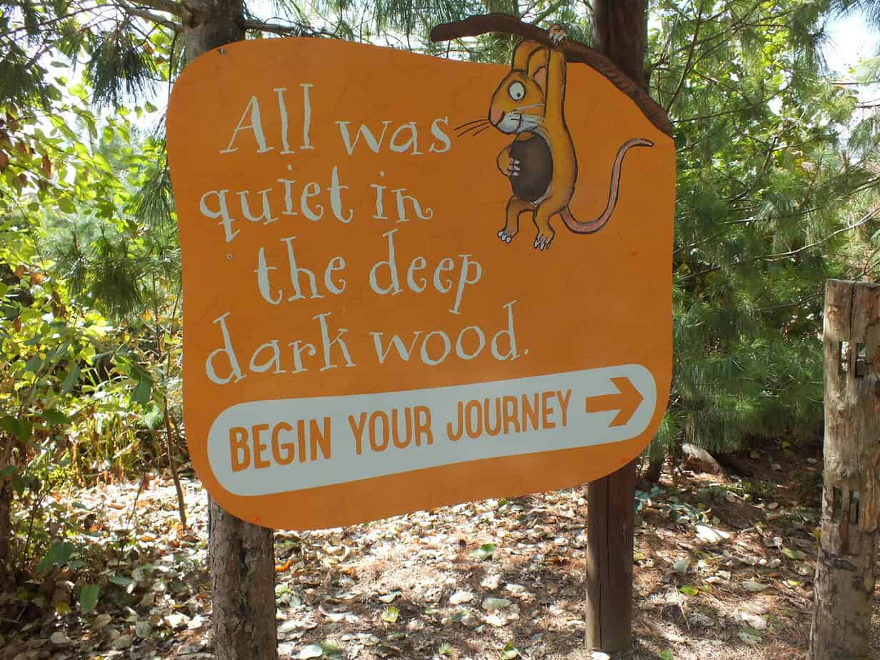 Orange woodland sign at Twycross Zoo illustrated with a mouse and reading "All was quiet in the deep dark wood. BEGIN YOUR JOURNEY". The themed trail is one of the additional family activities visitors can consider when asking whether Twycross Zoo Worth It.